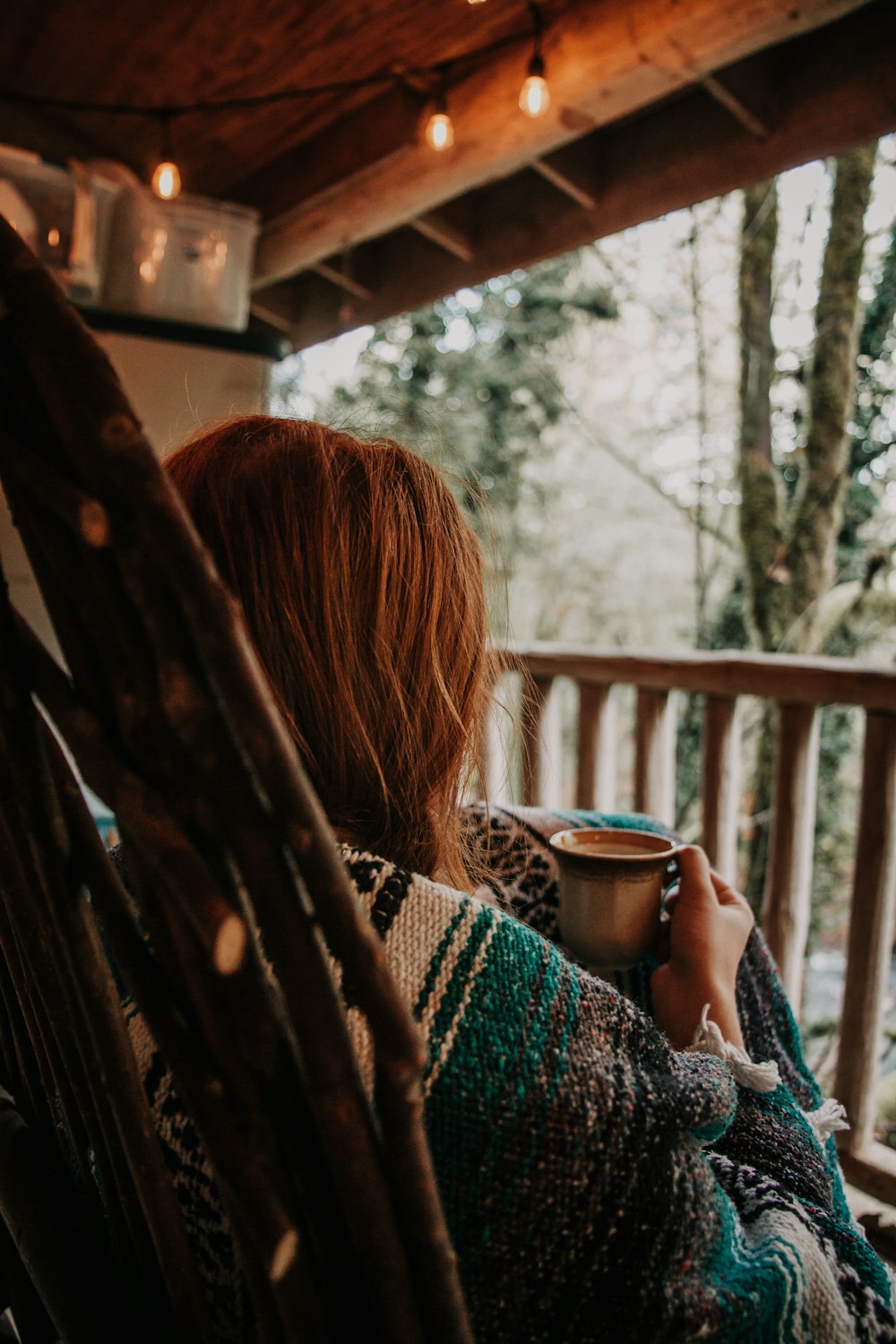 woman covering with blanket while holding cup