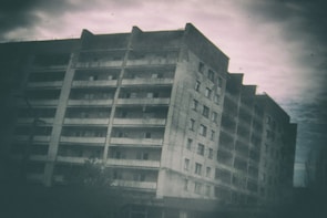 An old abandoned building with eerie glowing windows under a full moon.