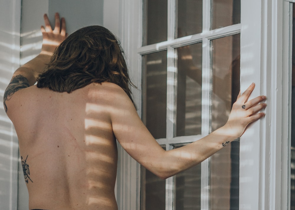 topless woman standing near window