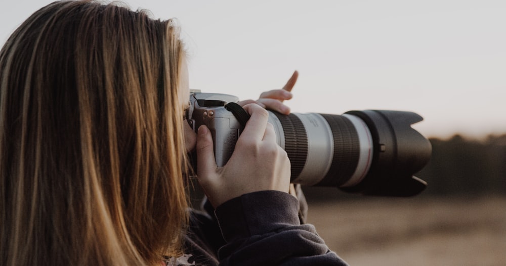 woman holding DSLR camera taking photo