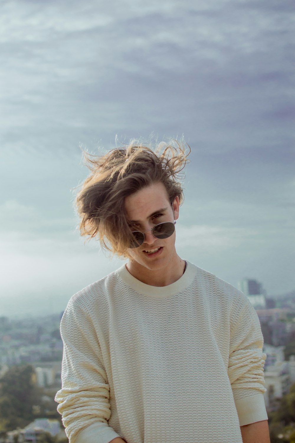 smiling man in beige knit crew-neck sweater standing high ground during daytime