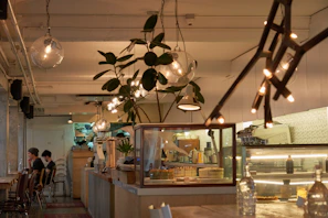 A cozy modern cafe corner with plush seating, warm lighting, and a customer enjoying a premium coffee and pastry