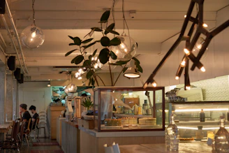 A cozy modern cafe corner with plush seating, warm lighting, and a customer enjoying a premium coffee and pastry