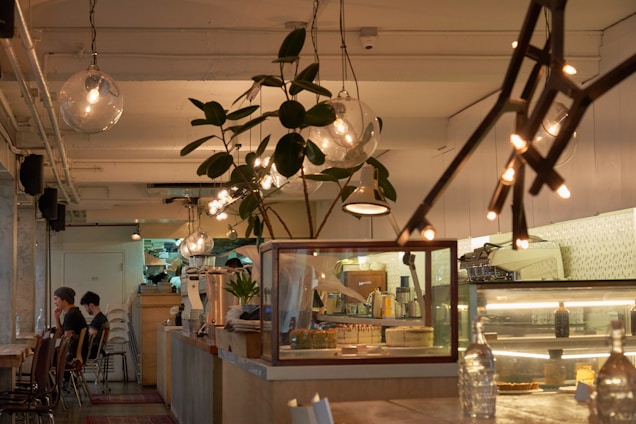 Cozy modern café interior with warm lighting and customers enjoying coffee.