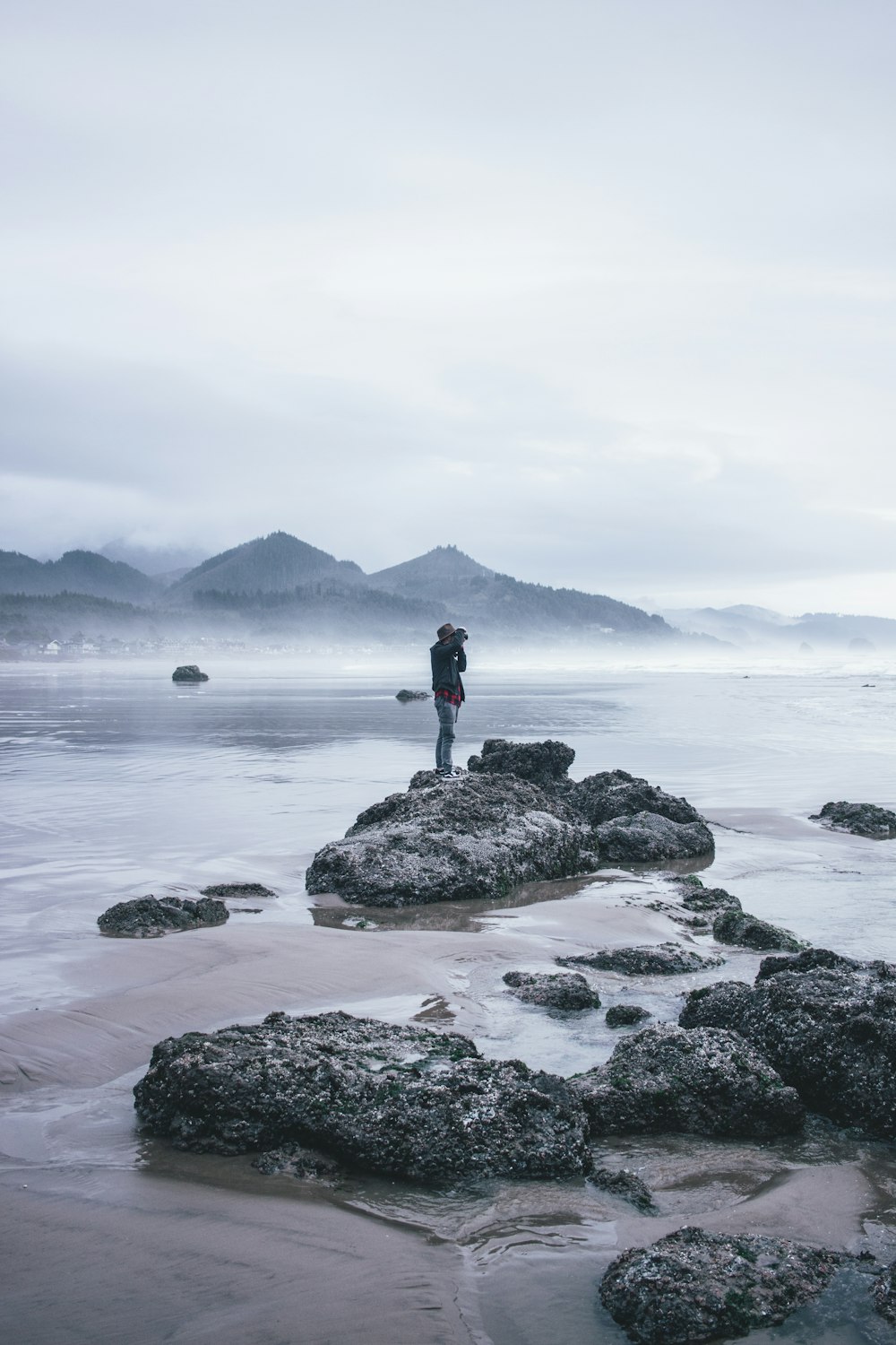 grayscale photography of man standing on rock