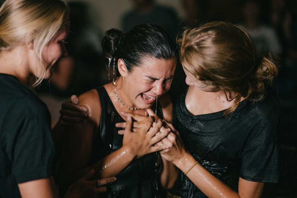 femme qui pleure entre deux femmes en chemises noires