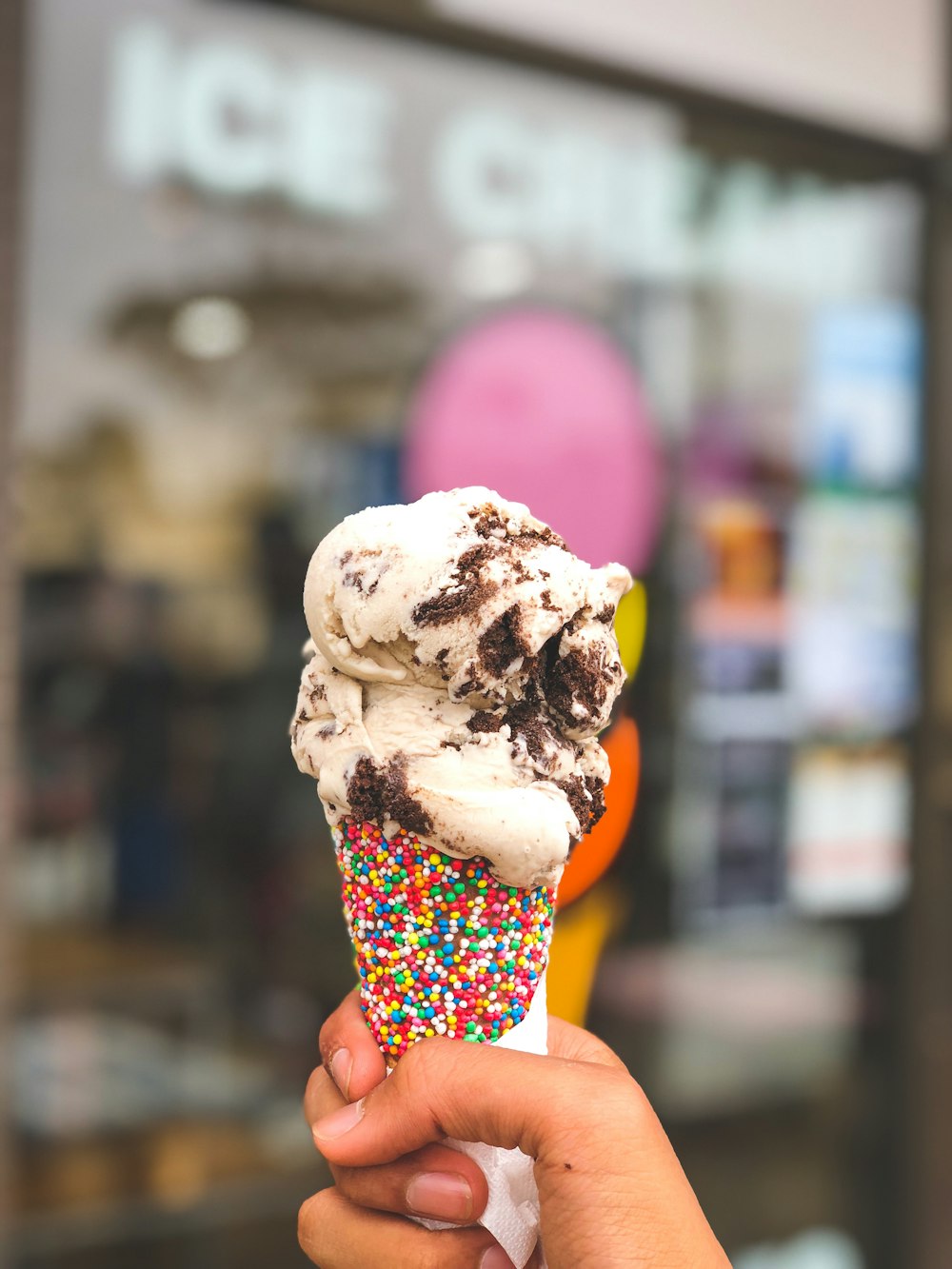 person holding candy sprinkled cone with ice cream