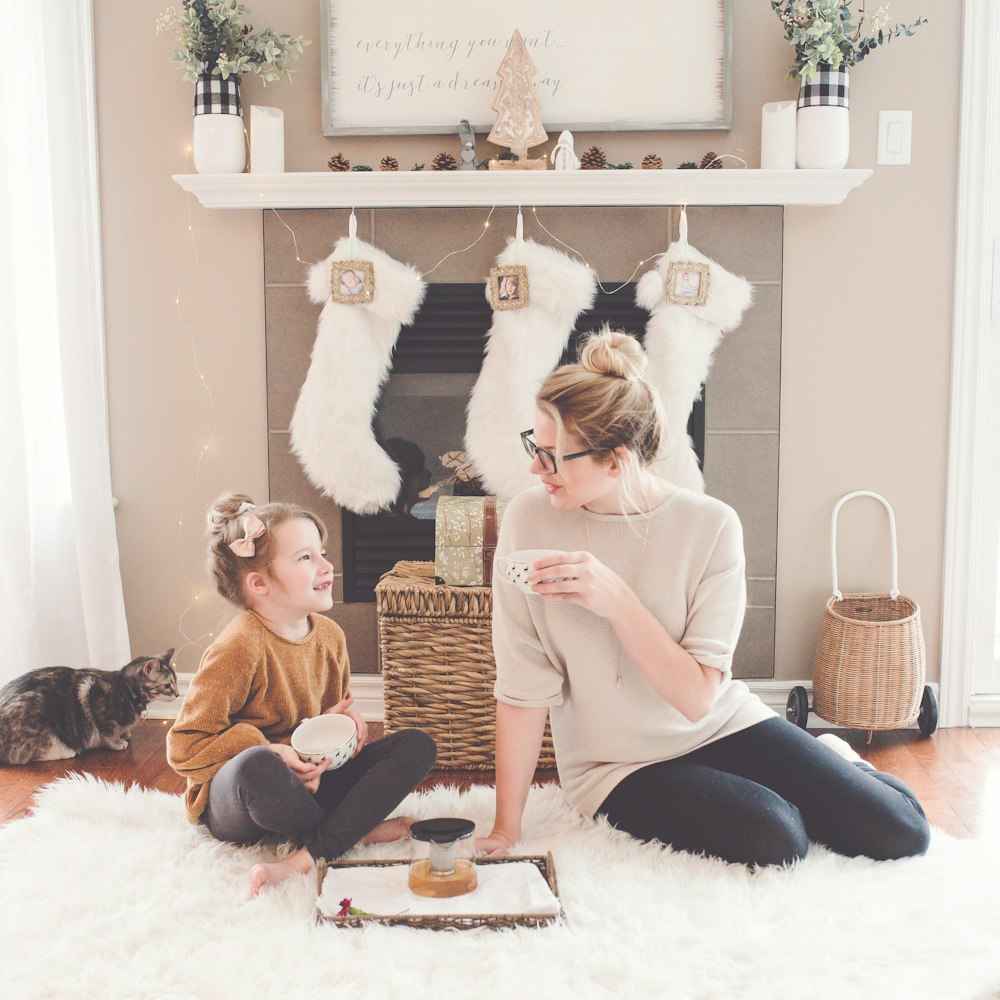 woman and girl sitting on white fur area rug