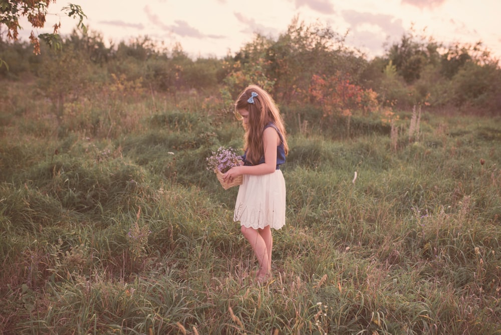 Mädchen mit Blumenkorb steht auf dem Rasenfeld