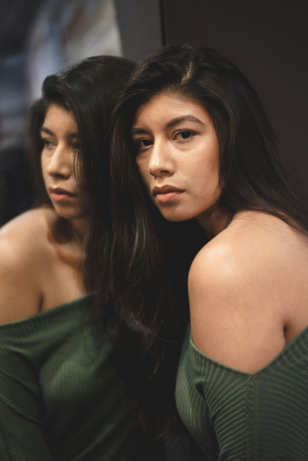 woman wearing green off-shoulder top in front of mirror inside room