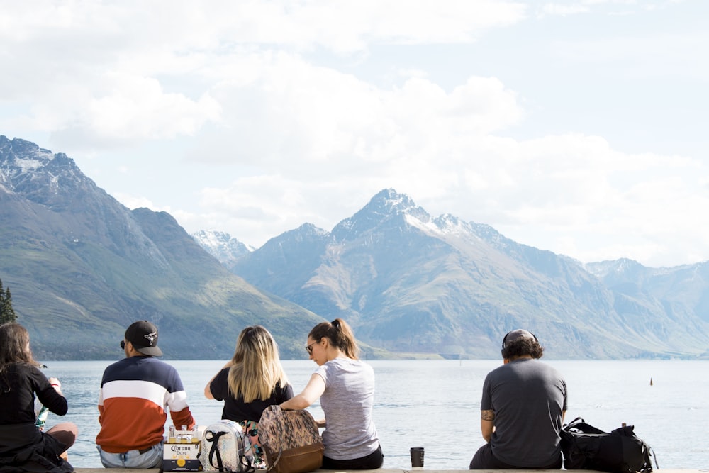 people sitting front of calm water at daytime