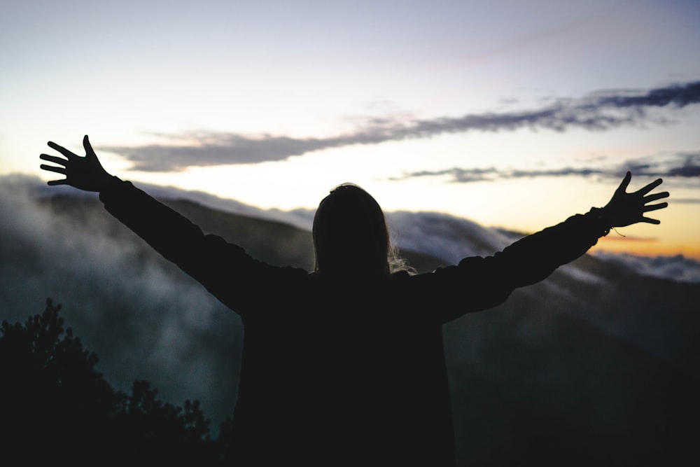 silhouette of man standing front of mountain