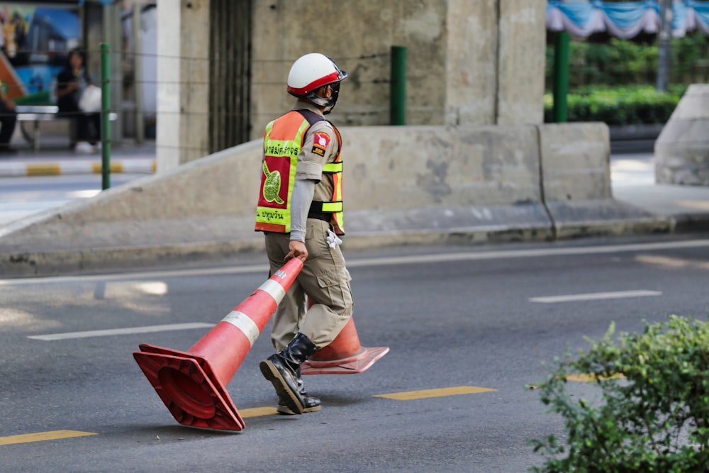 hombre tirando de conos de estacionamiento a lo largo de la carretera