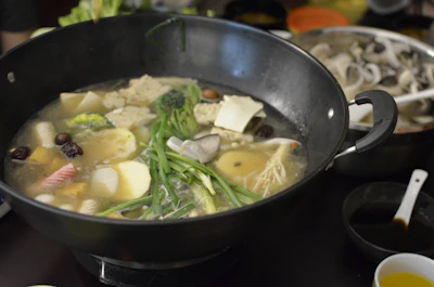 Traditional cooking pot simmering bakmi broth with natural ingredients.