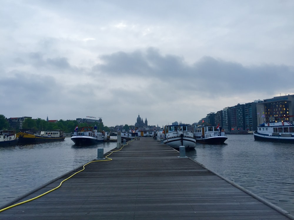 brown wooden dock beside yachts on canal