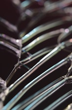 Close-up image of fractured glass with light reflecting off the jagged edges, creating a prismatic effect. The background is dark, enhancing the contrast with the intricate network of cracks.