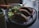 A plate with empanadas and a fresh salad, garnished with a rich sauce, is placed on a dark table. Nearby, there is a smoothie in a glass jar and various utensils.