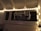 A string of fairy lights is arranged around a window, illuminating the word 'party' formed with metallic balloons. The setting appears to be indoors with white walls and a ceiling with rafters.