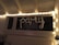 A string of fairy lights is arranged around a window, illuminating the word 'party' formed with metallic balloons. The setting appears to be indoors with white walls and a ceiling with rafters.