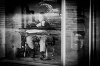 A candid photo of Krishna Ghosh sitting by a window, pen in hand, lost in thought.