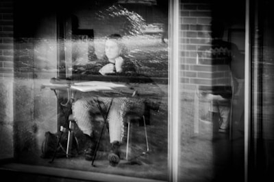 A candid photo of Krishna Ghosh sitting by a window, pen in hand, lost in thought.