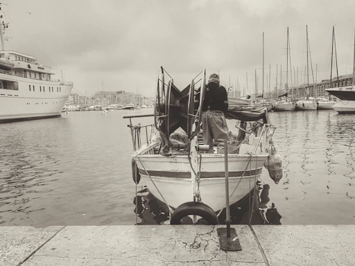 A friendly technician working on the electrical system of a small boat docked by a sunny marina.