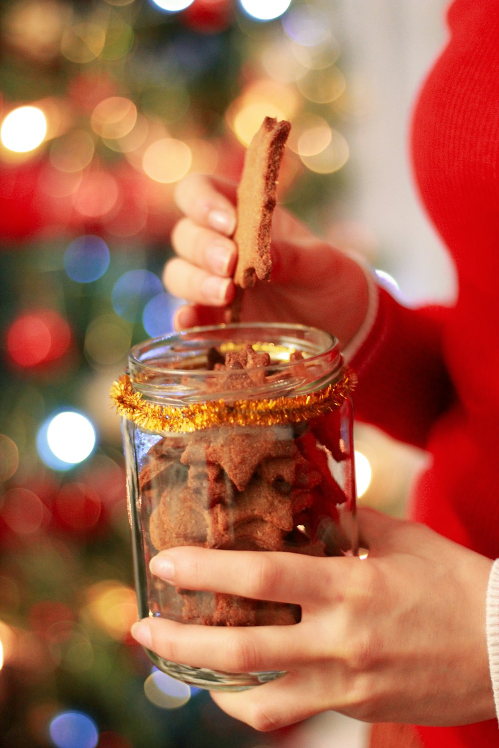 person holding clear jar filled with cookies
