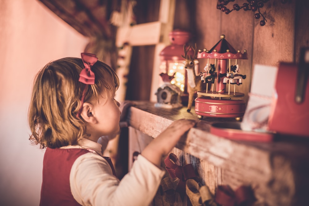 girl standing in front of carousel toy