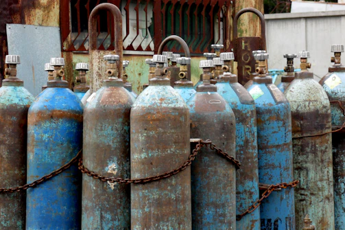 Close-up of colorful welding gas bottles lined up outdoors on a sunny day.