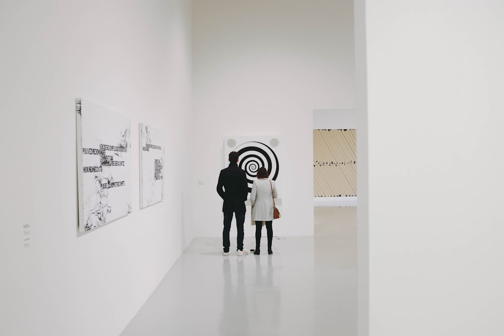 man and woman looking at white and black spiral painting