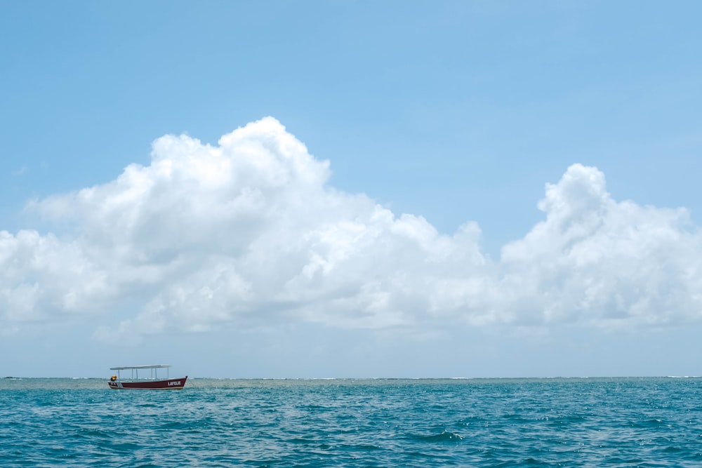 red boat sailing on ocean at daytime