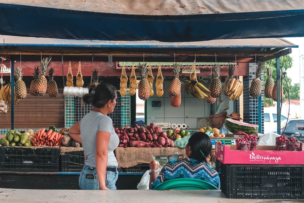 two women facing fruits and vegetable stall