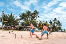 several men playing football on beach sand