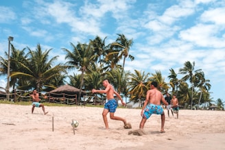 several men playing football on beach sand