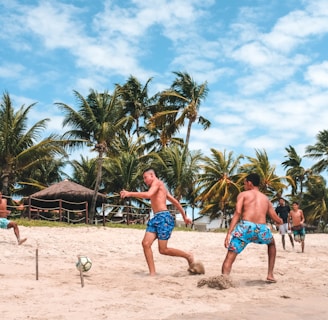 several men playing football on beach sand