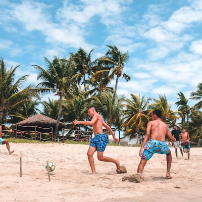 several men playing football on beach sand