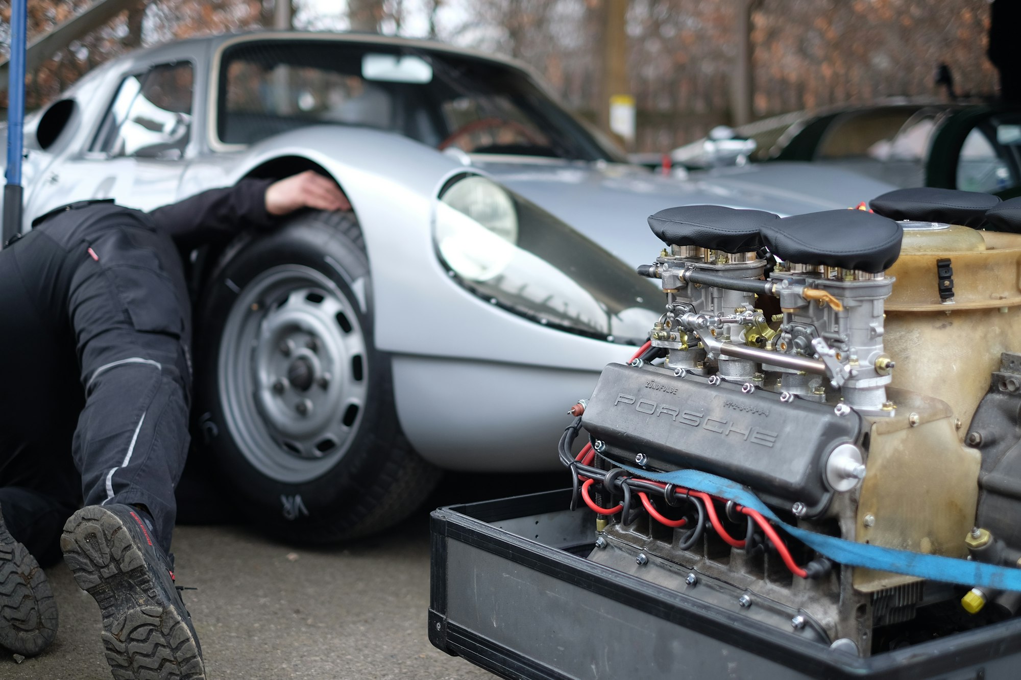 Taken at the 76th Goodwood Members’ Meeting at Goodwood Motor Circuit in Chichester, England. This photograph shows a preoccupied mechanic behind a selectively focused engine that was destined for this Porsche race car.