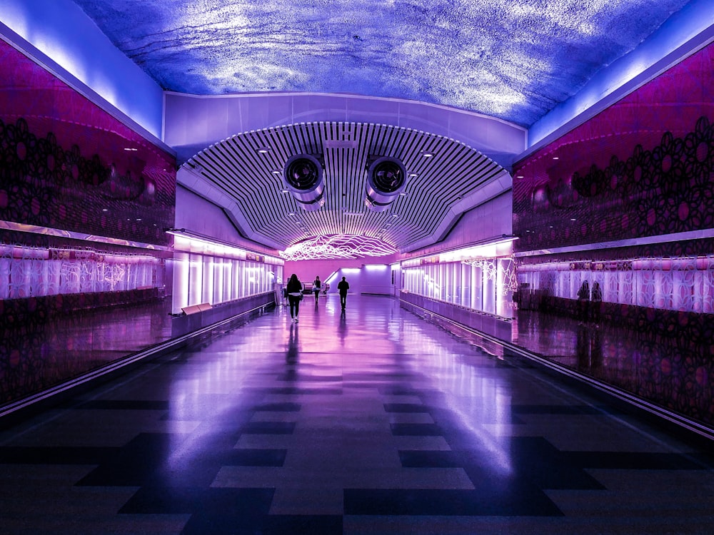 people walking in building with purple and blue lights