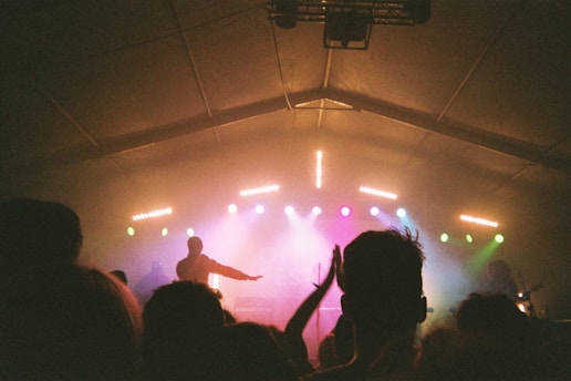 A moody, dark-toned photo of jrealityg performing live under vibrant stage lights.