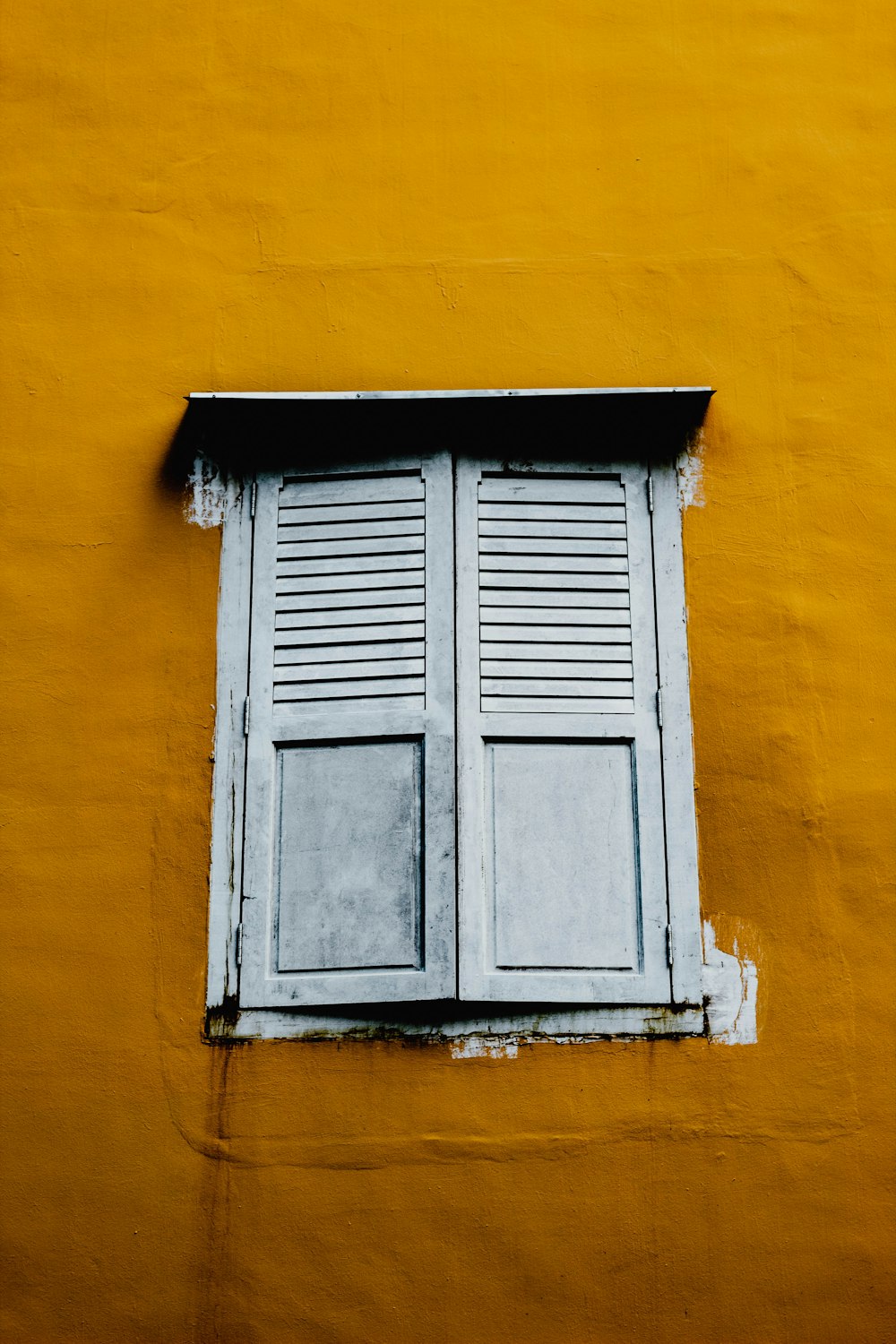 white wooden window closed on yellow building