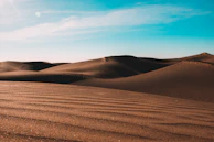 A peaceful desert scene with sand dunes under a bright blue sky.