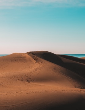 A serene desert landscape with soft sand dunes under a clear sky.