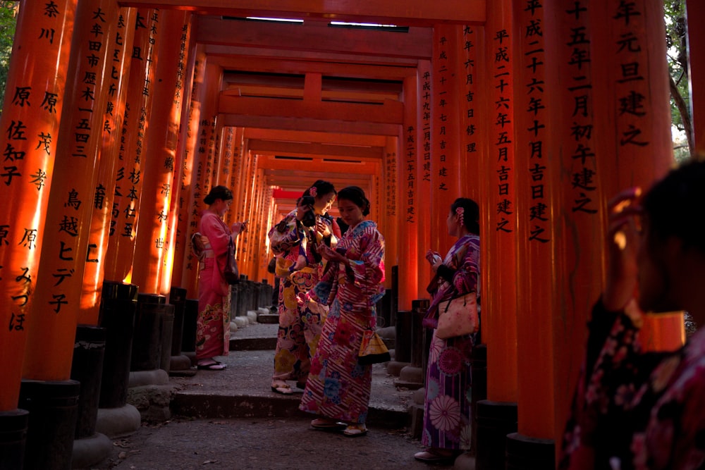 four women in kimono standing in tori gates