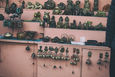 Display of antique metal showpieces and gift items arranged elegantly on a wooden shelf.
