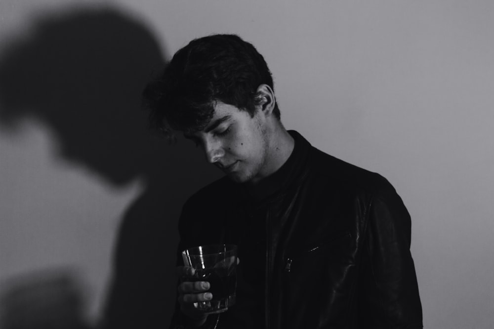 grayscale photography of man holding rock glass