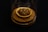 A small wooden bowl containing dried mealworms is placed on a wooden base, all under a transparent glass cover against a dark background.