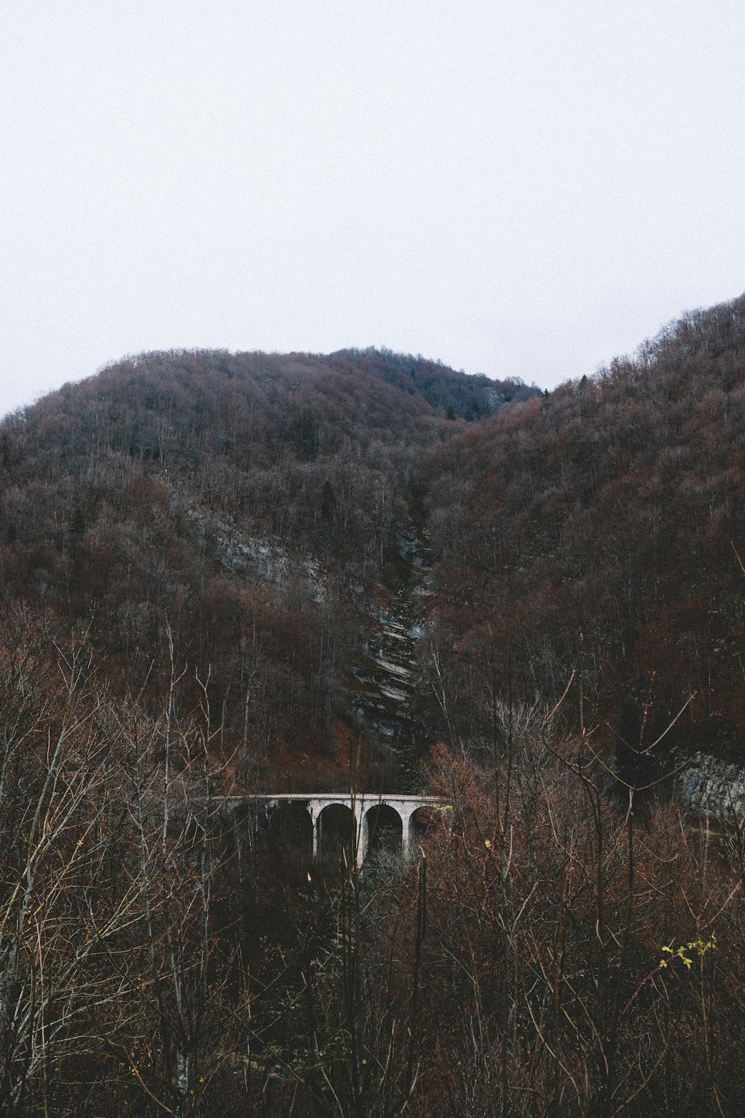 mountain with white concrete bridge under white sky