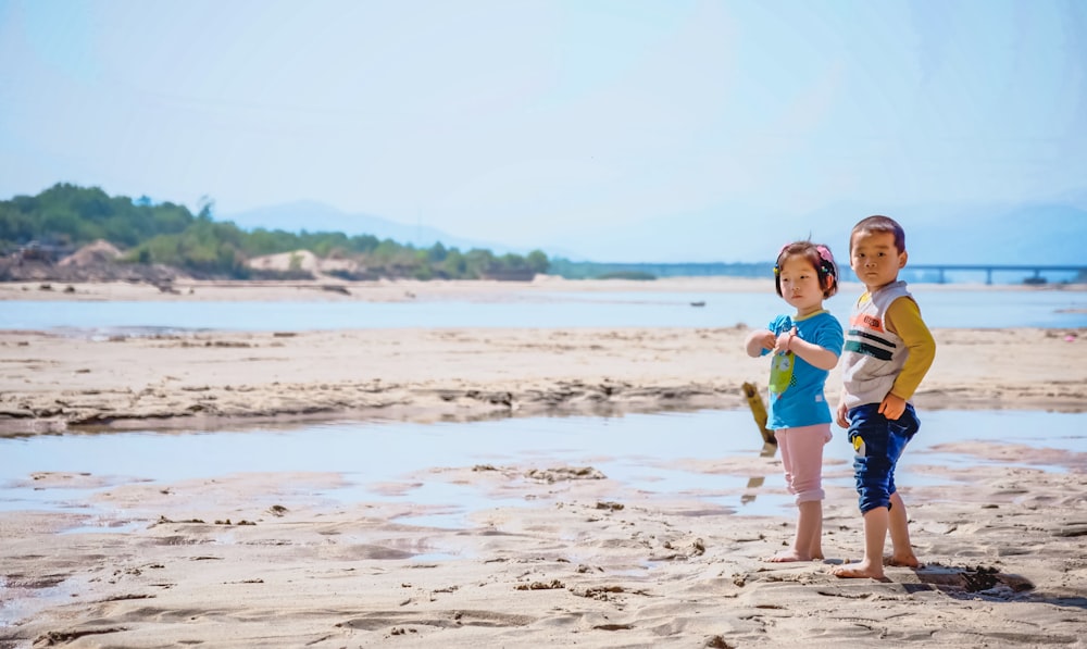 boy and girl standing on white sand
