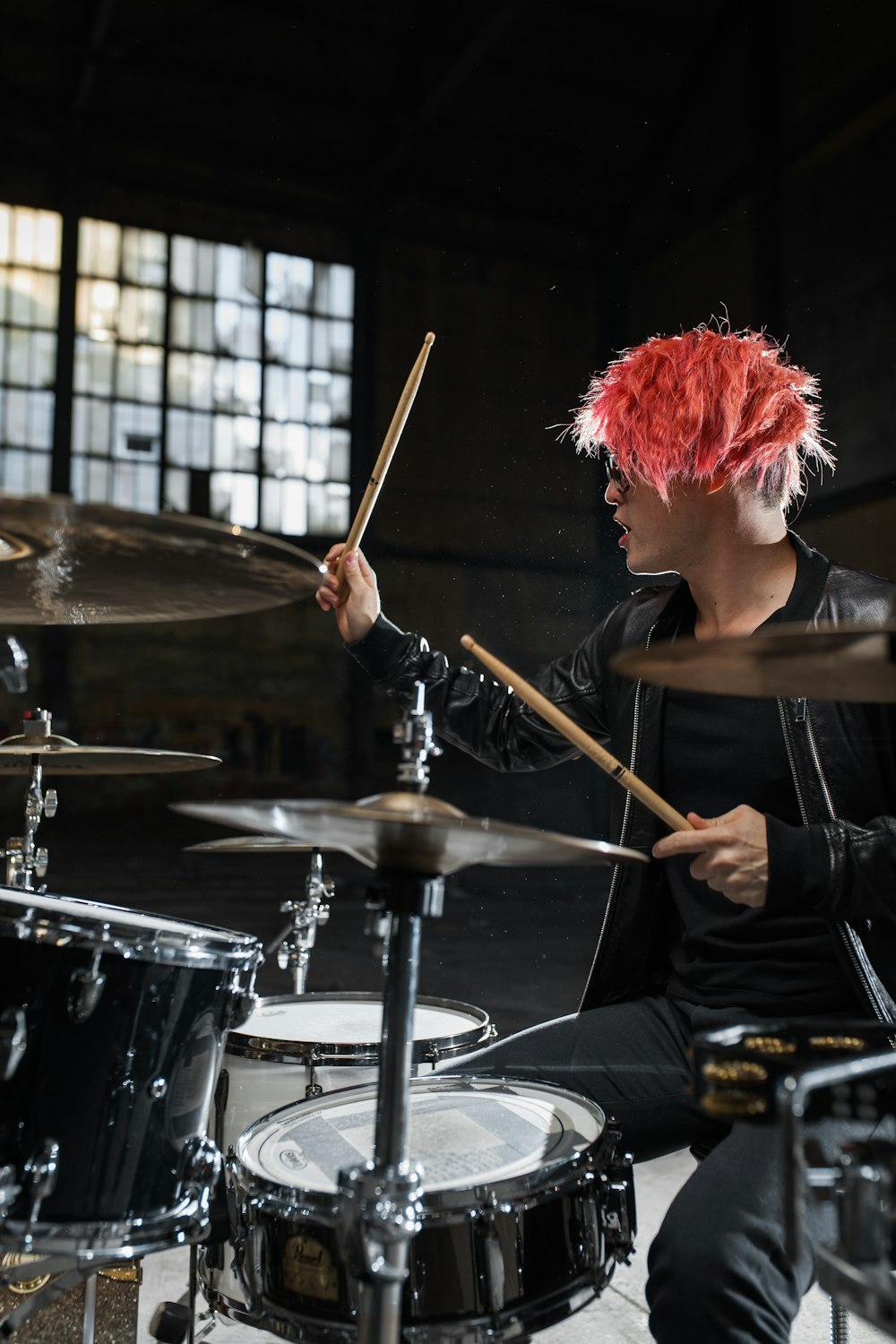 man wearing black jacket playing drum