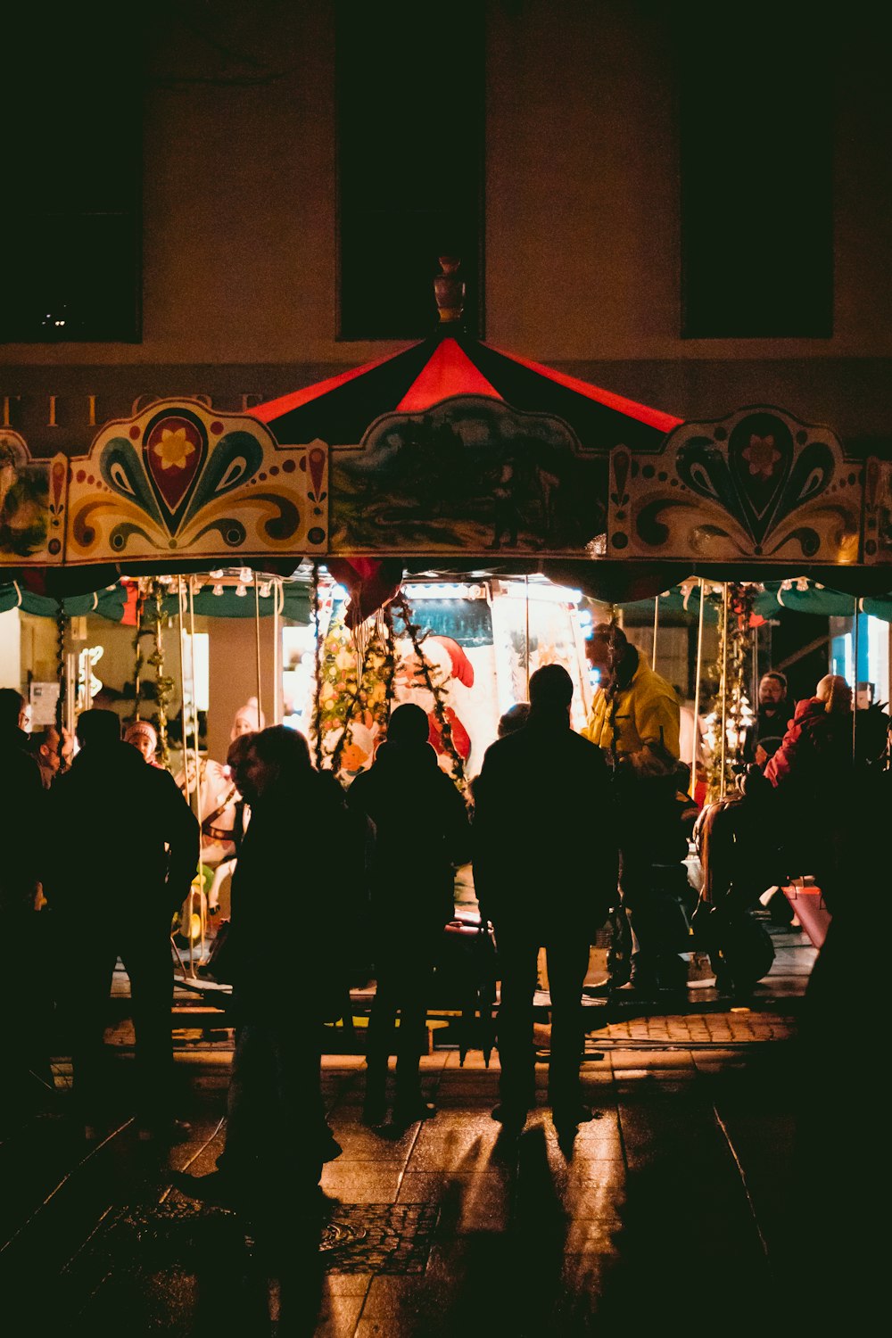 Gente montando y parando junto al tiovivo por la noche